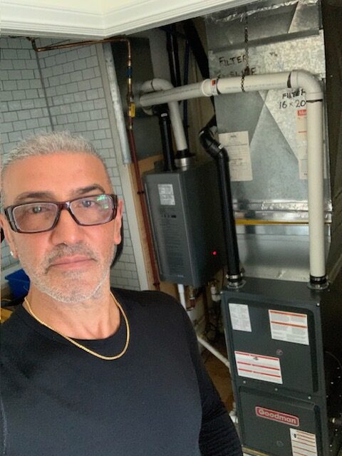 Experienced owner-operator of a certified gas fitting and plumbing company standing proudly in front of a furnace he installed.