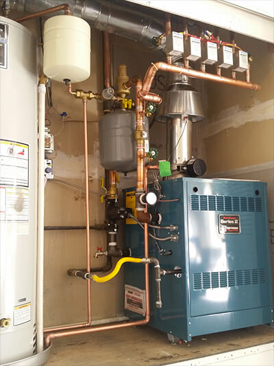 Experienced plumber performing maintenance on a modern residential boiler system in a home setting, ensuring efficient heating and energy savings.